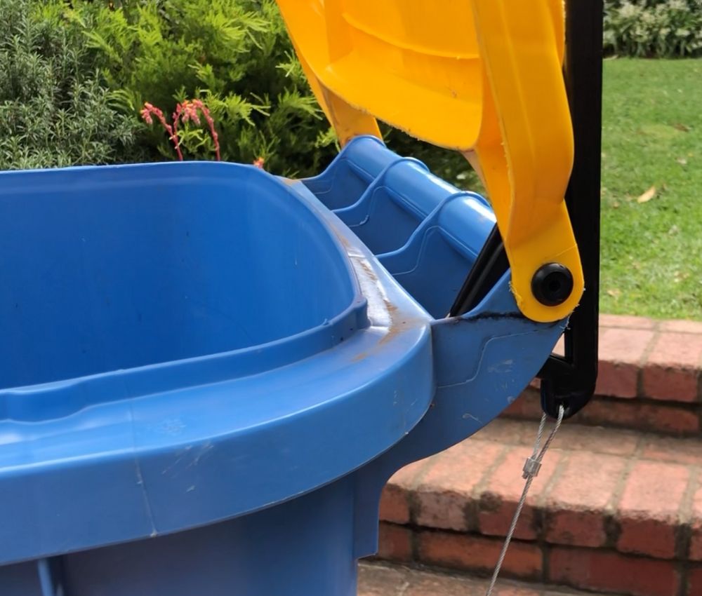 Close-up of the BLOP bin lid opener mechanism attached to a blue wheelie bin with its yellow lid raised