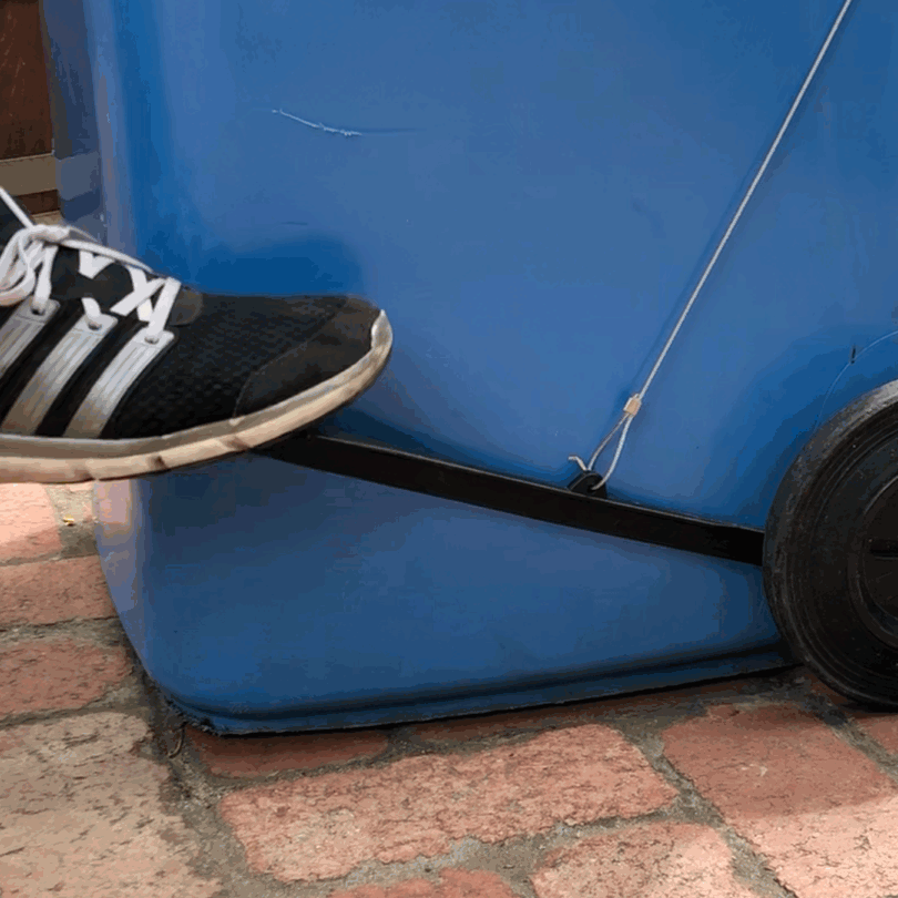 Person using a BLOP foot-operated bin lid opener on a blue wheelie bin with a yellow lid